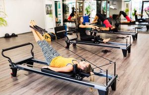 Trois jeune femmes réalisant des exercices de cardio pilates avec des machines de sport adaptées